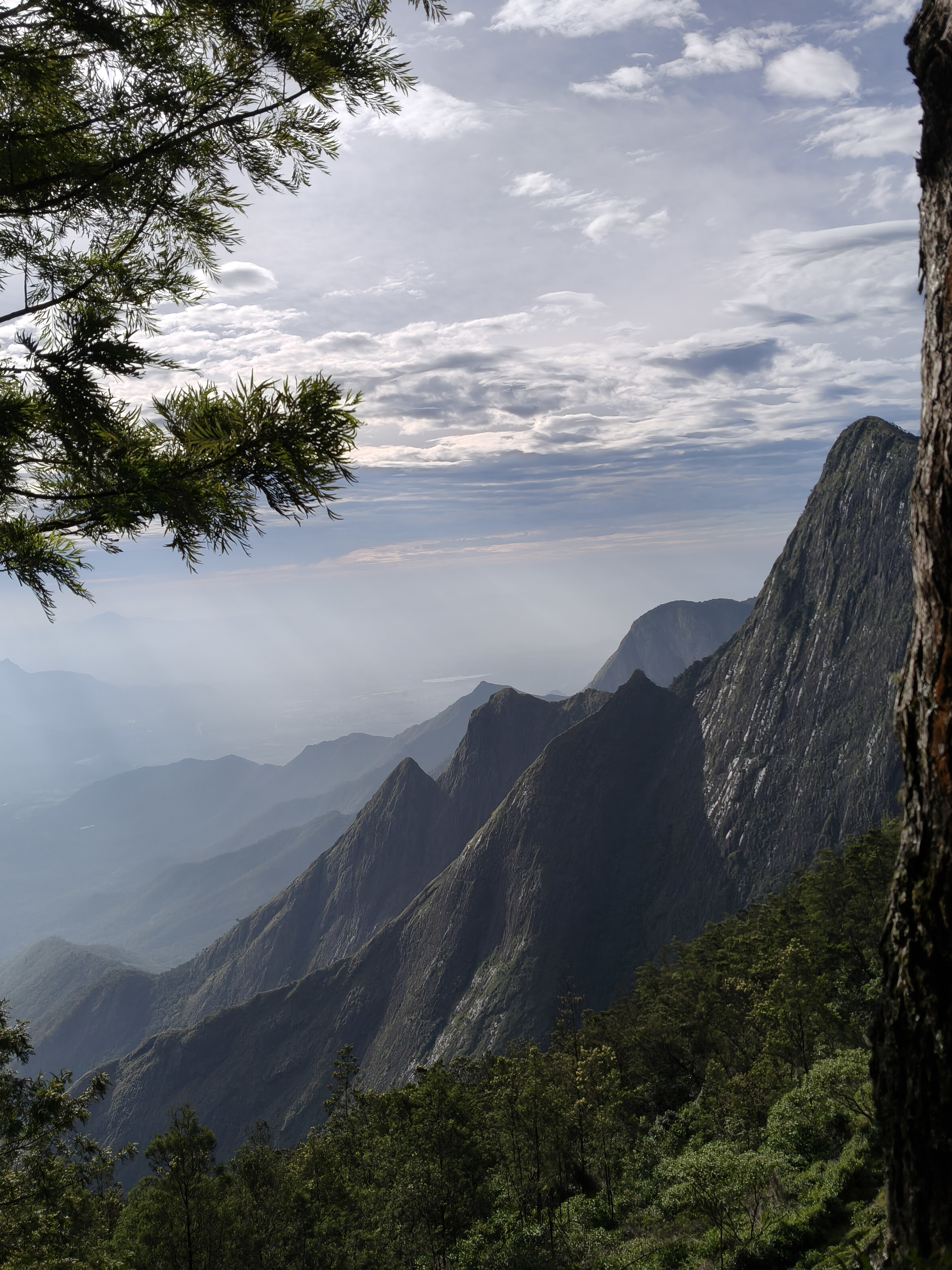 Kolukkumalai mountain cliffs with dramatic peaks and soft sunlight through clouds